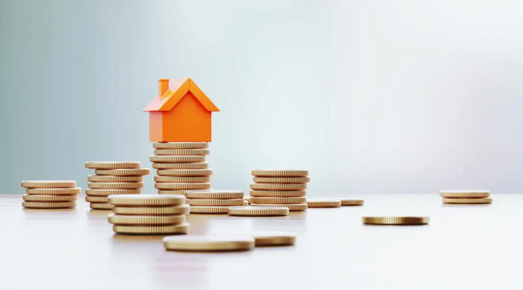 Small orange house model on stacks of coins representing rental cash flow