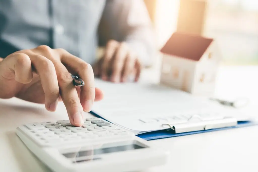 Calculator and small wooden house model used to work out the down payment on a rental property